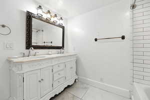 Full bathroom featuring double vanity, light marble finish floors, and tub / shower combination