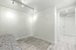 Unfurnished bedroom featuring light wood-style flooring and rail lighting