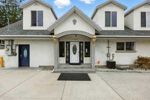 Doorway to property featuring stucco siding and roof with shingles