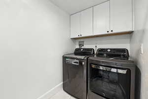 Laundry room featuring cabinet space, separate washer and dryer, and light tile patterned floors