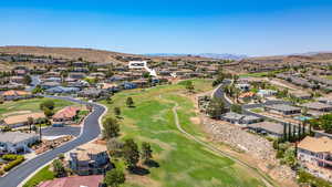 Aerial perspective of suburban area featuring a golf club and a mountainous background