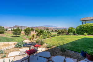 View of green lawn with a patio and a mountain view