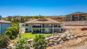 Rear view of house with a tiled roof, a lawn, a patio, stucco siding, and stairs