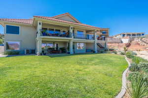 Rear view of house with stucco siding, stairs, a yard, a patio area, and a tiled roof