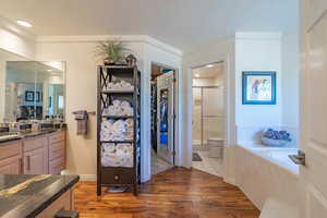 Bathroom featuring light wood-type flooring, a stall shower, vanity, a bath, and a textured ceiling