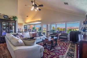 Living room with ceiling fan, high vaulted ceiling, wood finished floors, and crown molding