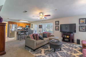 Living room with light carpet, a textured ceiling, and a ceiling fan