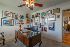 Home office with carpet flooring and ceiling fan