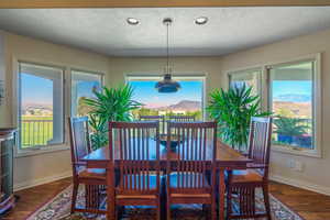 Dining room with a textured ceiling, dark wood-style flooring, recessed lighting, and a mountain view
