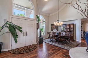 Foyer entrance with a high ceiling, dark wood finished floors, ornamental molding, and a chandelier