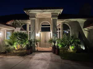 Exterior entry at twilight with stucco siding
