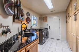 Laundry room featuring light tile patterned floors, washing machine and clothes dryer, and cabinet space
