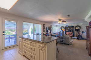 Kitchen featuring dark stone counters, a kitchen bar, a kitchen island, a textured ceiling, and a ceiling fan