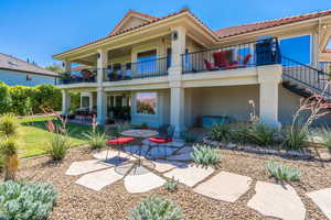 Rear view of property with a tile roof, a patio area, stucco siding, and a balcony