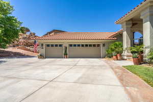 View of front of property featuring a garage, driveway, a tile roof, and stucco siding