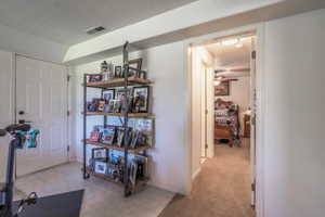 Hall with a textured ceiling, light tile patterned floors, and light carpet