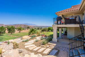 View of green lawn with a patio area, stairway, a mountain view, and a balcony