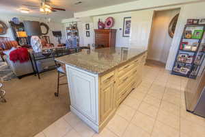 Kitchen with a breakfast bar, dark stone counters, light tile patterned floors, a ceiling fan, and open floor plan