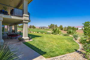 View of green lawn featuring a balcony, a mountain view, a patio, and golf course view