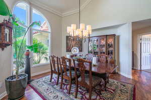 Dining room with crown molding, dark wood finished floors, and a chandelier