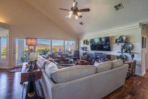 Living room with high vaulted ceiling, dark wood-style flooring, ceiling fan, a textured ceiling, and crown molding