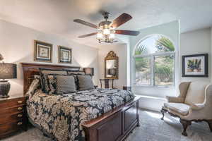 Carpeted bedroom with a textured ceiling and ceiling fan