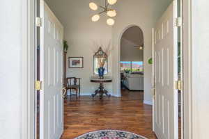 Foyer featuring arched walkways, dark wood finished floors, a chandelier, and a ceiling fan