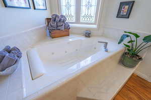 Full bathroom featuring a tub with jets and wood finished floors