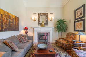 Living room featuring a glass covered fireplace, ornamental molding, and wood finished floors