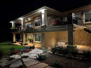 Back of house at twilight with a patio, stucco siding, and a balcony