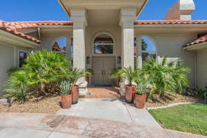 View of exterior entry with a tile roof and stucco siding