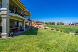 View of green lawn with a balcony, stairs, a patio area, and view of golf course