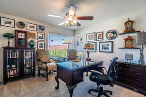 Carpeted home office with a textured ceiling and a ceiling fan