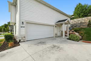 View of side of property featuring driveway, an attached garage, and stone siding