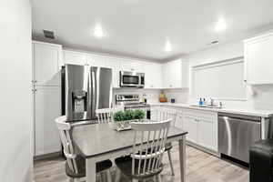 Kitchen featuring light countertops, stainless steel appliances, white cabinetry, and recessed lighting