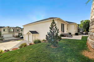View of home's exterior with a lawn, a garage, concrete driveway, and a patio