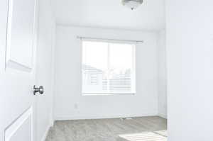 Spare room with baseboards and light carpet