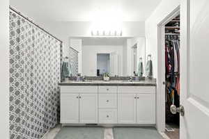 Full bathroom featuring double vanity and a walk in closet