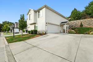 View of property exterior featuring driveway, a lawn, and a garage