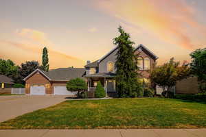 View of front of home with a porch, a lawn, concrete driveway, an attached garage, and brick siding