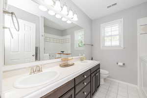 Bathroom featuring light tile patterned floors, double vanity, and a shower