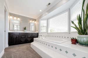 Primary bathroom featuring a garden tub, double vanity, ornamental molding, and recessed lighting