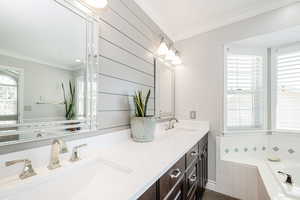 Full bath featuring crown molding, double vanity, and a bath