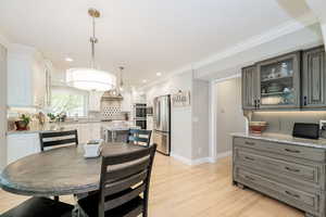 Eat in kitchen space featuring light wood-type flooring, crown molding, and built-in cabinetry.