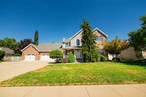 View of front facade with a porch, concrete driveway, a garage, brick siding, and a chimney