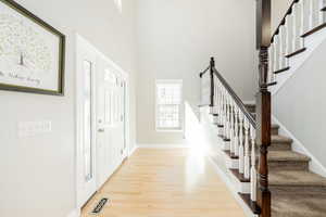Entryway with stairway, light wood finished floors, and a high ceiling