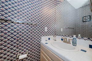 Bathroom with wallpapered walls and vanity