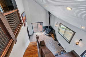 Stairs featuring a wood stove, high vaulted ceiling, and wood finished floors