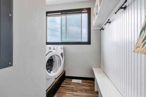 Laundry room featuring wood finished floors, electric panel, and washer and dryer