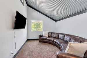Carpeted living area with vaulted ceiling and baseboards